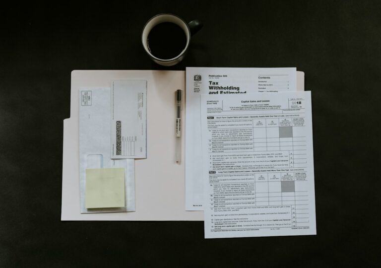 Formularios tributarios, bolígrafo y taza sobre un escritorio