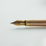 Pluma estilográfica dorada sobre superficie blanca