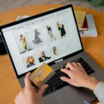 Mujer realiza una compra en línea con tarjeta de crédito desde su computador portátil en una tienda de ropa