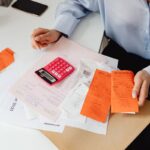 Persona revisa recibos y hace cuentas con una calculadora en su escritorio