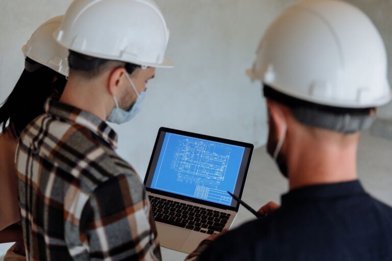 Oficio 016896 del 25-09-2026. IVA. Base gravable especial AIU en contrato de reforzamiento estructural de un inmueble. 4 Ingenieros con casco revisan un plano de construcción en un portátil