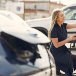 Mujer carga un vehículo eléctrico en una estación de la ciudad