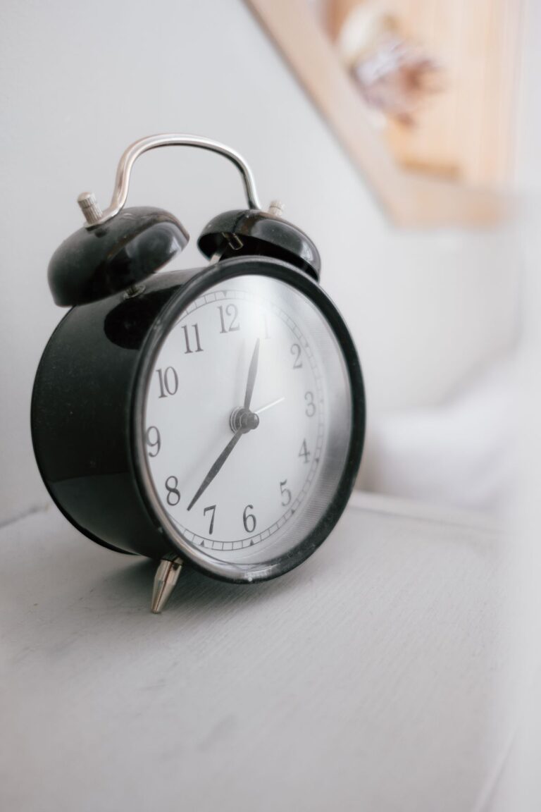 Reloj despertador negro con campanas sobre una mesa blanca
