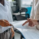 Dos colegas leen y comentan un informe financiero en una oficina