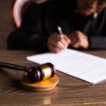 Oficio 016603 del 21-09-2026. Renta. Pagos que integran la base de la renta exenta del num. 7 del art. 206 del E.T. para funcionarios judiciales. Juez firma documentos en su escritorio junto a un mazo