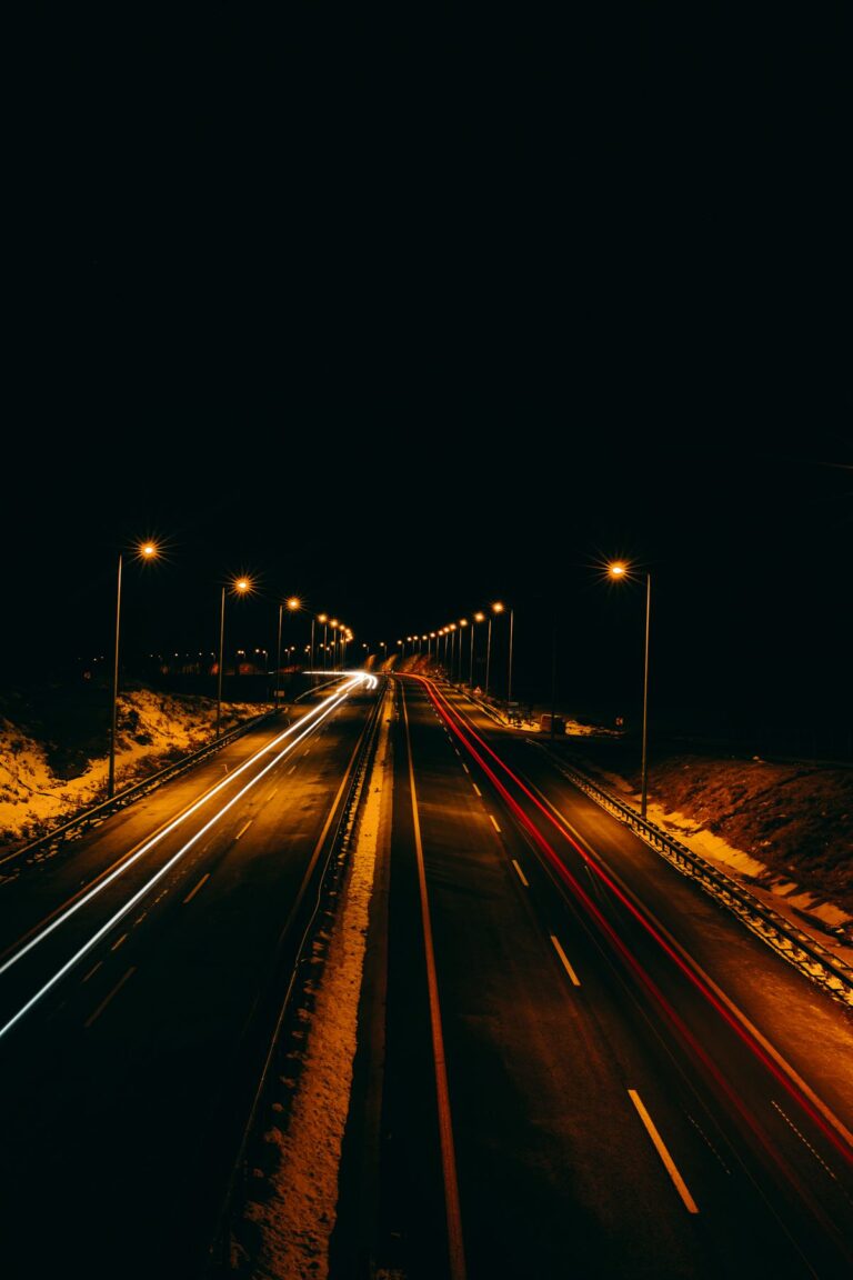 Vía iluminada por postes de alumbrado público en la noche